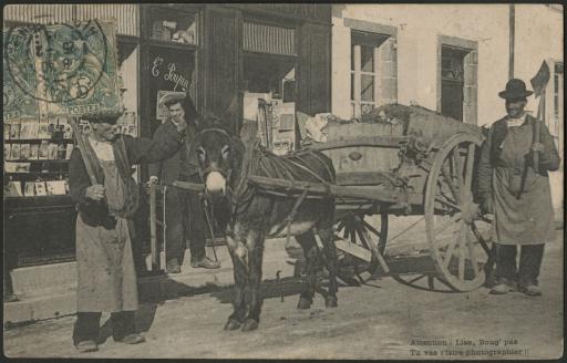 Mortagne-sur-Sèvre. - La façade de la boutique de photographies et de cartes postales d'Eugène Poupin. Au premier plan, des ouvriers avec un âne attelé à une charrette.